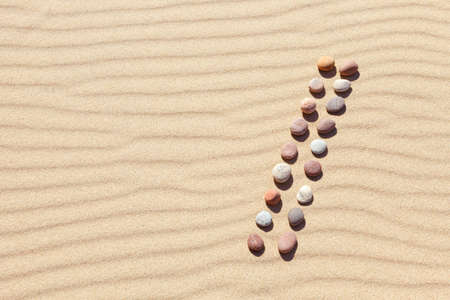 Pattern of colored pebbles on clean sand. The concept of peace and contemplation. Flat lay, top...