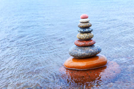 Rock Zen pyramid of colorful pebbles standing in the water. Concept of tranquility, balance, harmony...