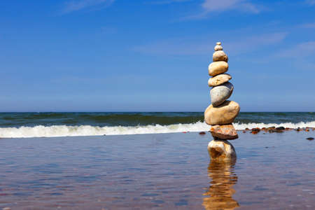 Rock zen pyramid of colorful pebbles standing in the water on the background of the sea. Concept of...