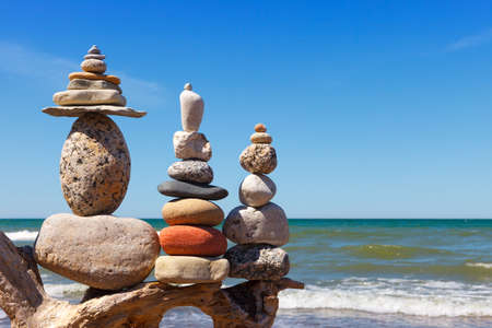 Three Rock Zen pyramid of balanced stones on a background of the summer sea and blue sky. Concept of spiritual harmony, balance and meditationの写真素材