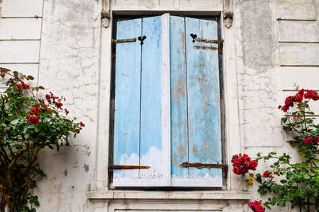 Closed wooden shutters of blue color on the window of the old houseの写真素材