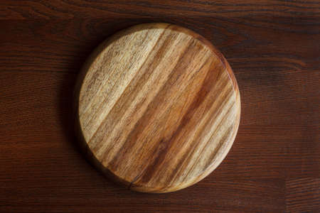 An empty, clean cutting board with a beautiful texture on a dark wooden table. Top viewの写真素材