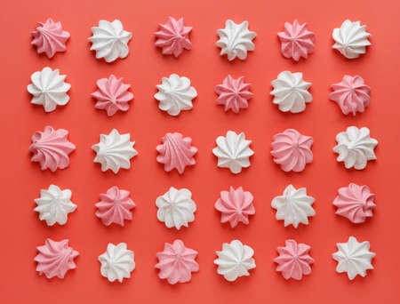 Pattern of pink and white meringues on a red background. Flat lay, Top viewの写真素材