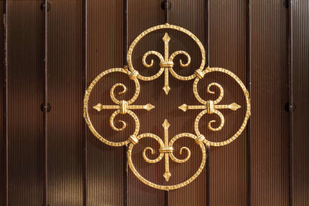 Metal forged pattern painted with gold color paint, decorating a fence or gate. Close-up