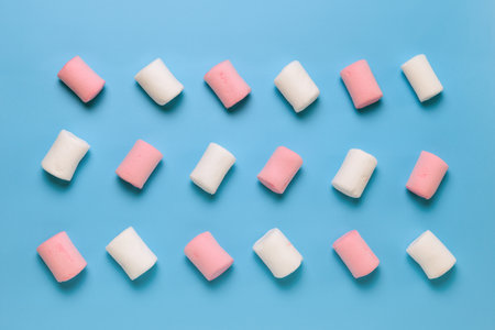 White and pink marshmallow on a blue background. top view. flat layの写真素材