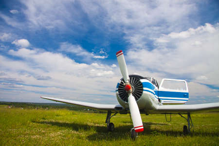 Propeller plane on the aerodrome on cloudy sky background