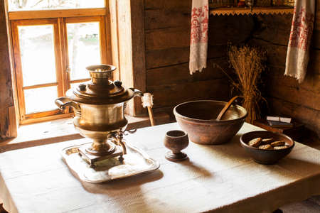 Russian still life with a samovar, wooden dishes and wooden cup on the table covered with white clothの写真素材