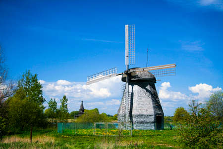 Wooden windmill in the countryside on blue sky background