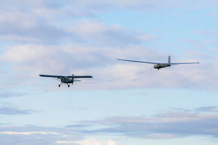 Propeller plane towing a glider in a cloudy skyの写真素材