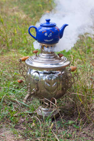 Russian samovar smoking with a blue teapot on itの写真素材