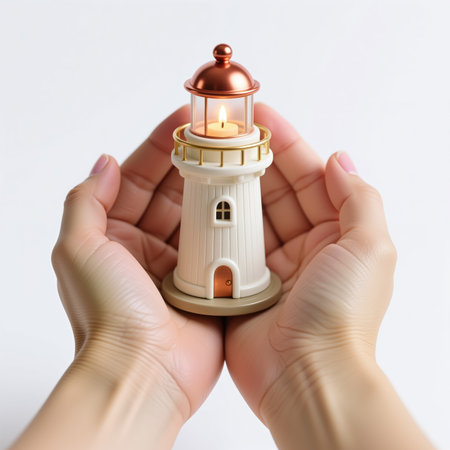 A pair of cupped hands cradling a small, intricately designed white and gold lighthouse with a lit candle inside, symbolizing safety and guidance.の素材