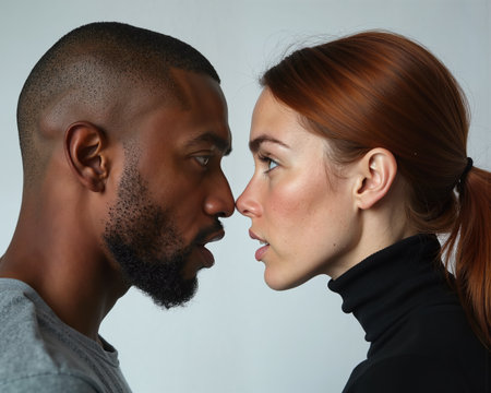 Man and woman with intense gazes and subtle smiles, their faces inches apart, conveying a sense of closeness and connection.の素材