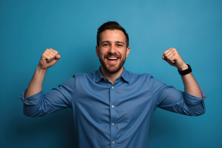 A joyful and triumphant man with a broad smile, flexing his arms in celebration against a blue background.の素材