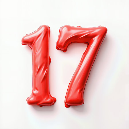 A pair of shiny red balloons shaped as numbers 17, celebrating a 17th birthday against a light pink background.の素材