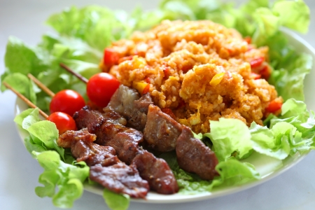 fried pieces of pork on a stick with rice are on a plate の写真素材