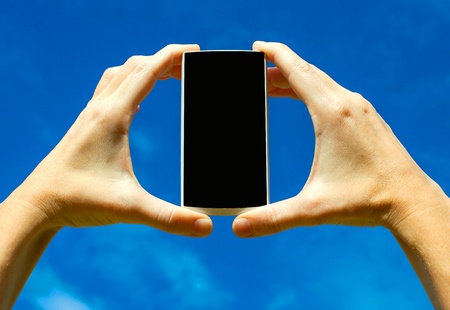 Mobile phone in the hand   on background of  the sky  の写真素材