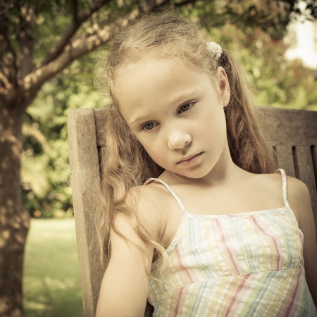 sad girl sitting on a chair in the gardenの写真素材