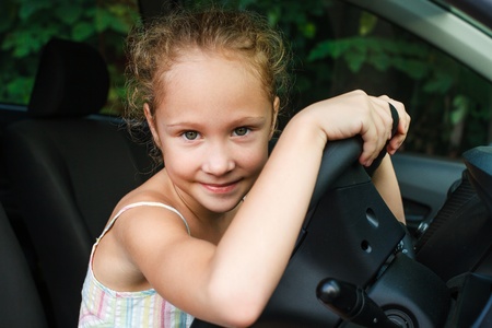 little girl sitting in the car and holding the steering wheelの写真素材