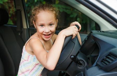 little girl sitting in the car and holding the steering wheelの写真素材
