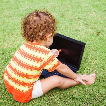 Child with laptop on a  meadowの写真素材