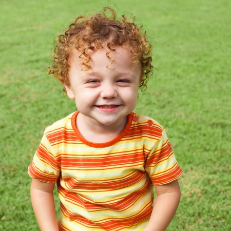 happy little boy sitting on the grass in the gardenの写真素材