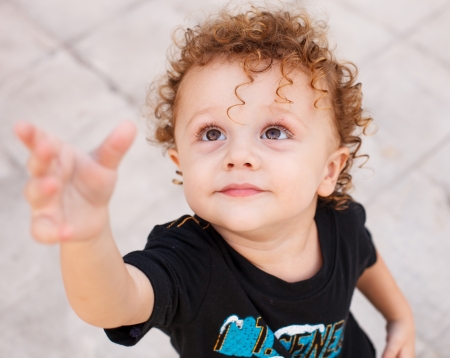 Above view of happy child standing at road and raising her arms to camera