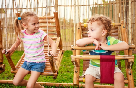 happy little girl and boy on a swingの写真素材