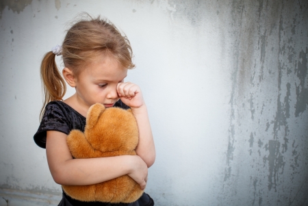 sad little girl on background the wall with toyの写真素材