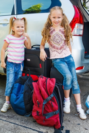 two little girls standing near the car with backpacksの写真素材