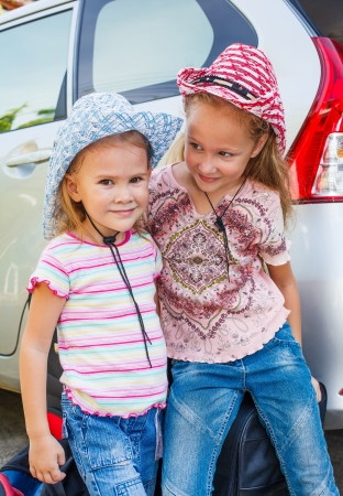 two little girls standing near the car with backpacksの写真素材