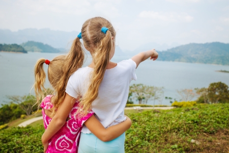 Two girls standing on the beach and watching the lakeの写真素材