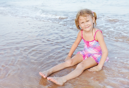 Adorable happy smiling girl  sitting on beach の写真素材