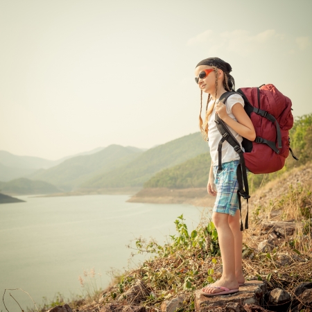 little girl with backpack afternoon on the lake shoreの写真素材