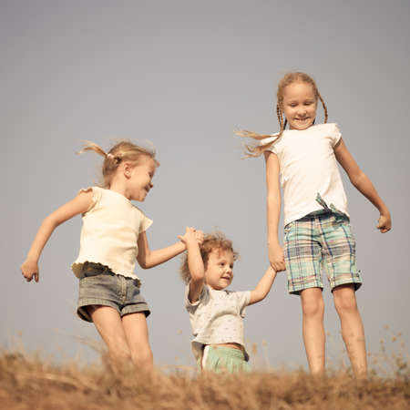 two little girls and little boy dancing on the roadの写真素材