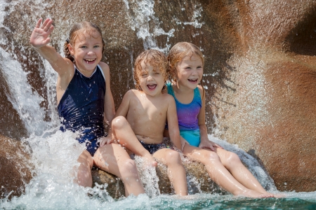 three happy kids sitting near the pool in the waterparkの写真素材