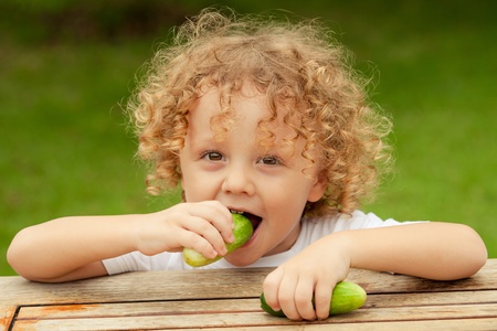 Happy little boy holding a  cucumber  Concept of healthy food の写真素材