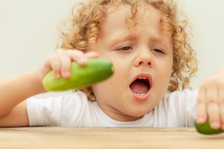 Happy little boy holding a  cucumber  Concept of healthy food の写真素材