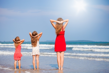 mother and two daughters standing on the beachの写真素材