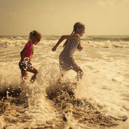 Happy kids running at the beach in the day timeの写真素材