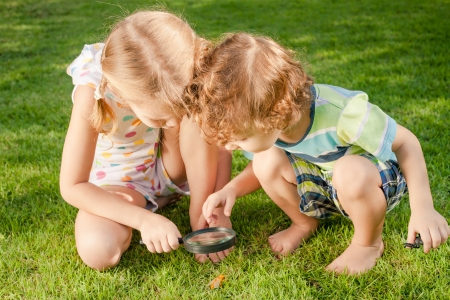 Two little kids  playing with magnifying glass outdoors in the day timeの写真素材