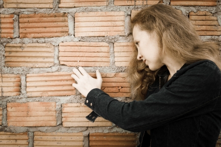 one sad woman sitting  near a brick wallの写真素材