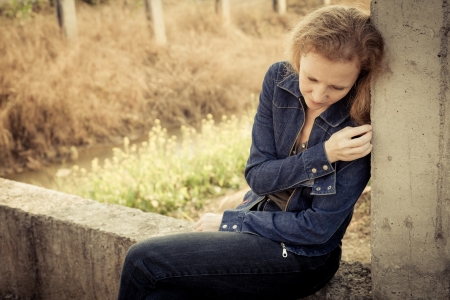 one sad woman sitting  near a  wallの写真素材