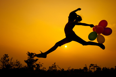 teen girl with balloons jumping on the nature of the eveningの写真素材