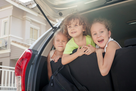 three happy kids sitting in the carの写真素材