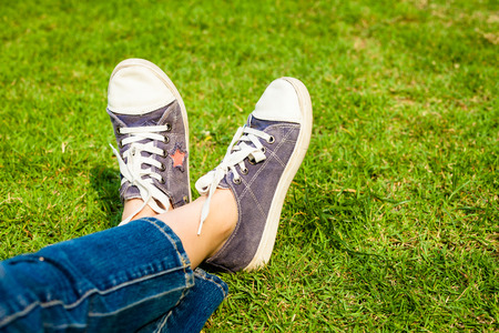 youth sneakers on girl legs on grass during sunny serene summer day の写真素材