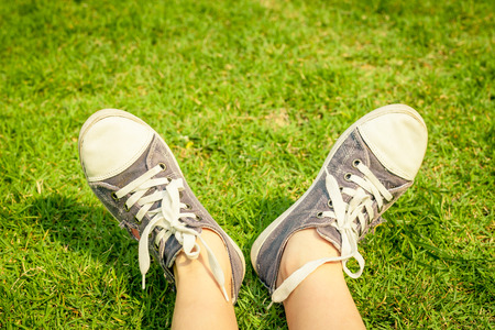 youth sneakers on girl legs on grass during sunny serene summer day 