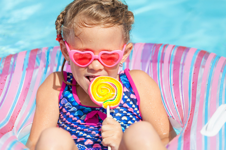 little girl with lollipop lying on the  inflatable rubber circle  in the swimming poolの写真素材