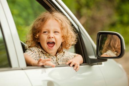Portrait of a screaming little boy who sitting in the carの写真素材