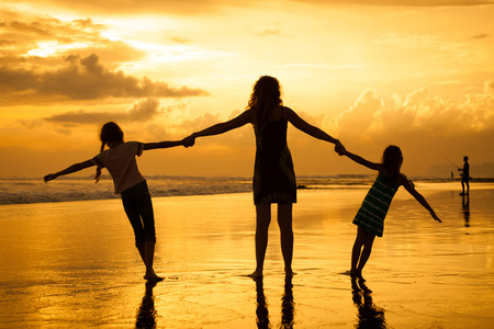Happy family playing at the beach in the dawn timeの写真素材