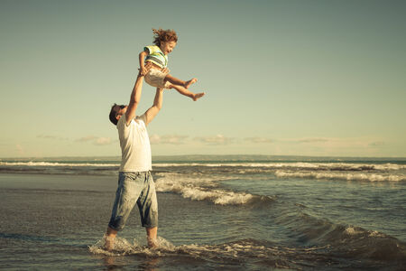father and son playing on the beach at the day timeの写真素材
